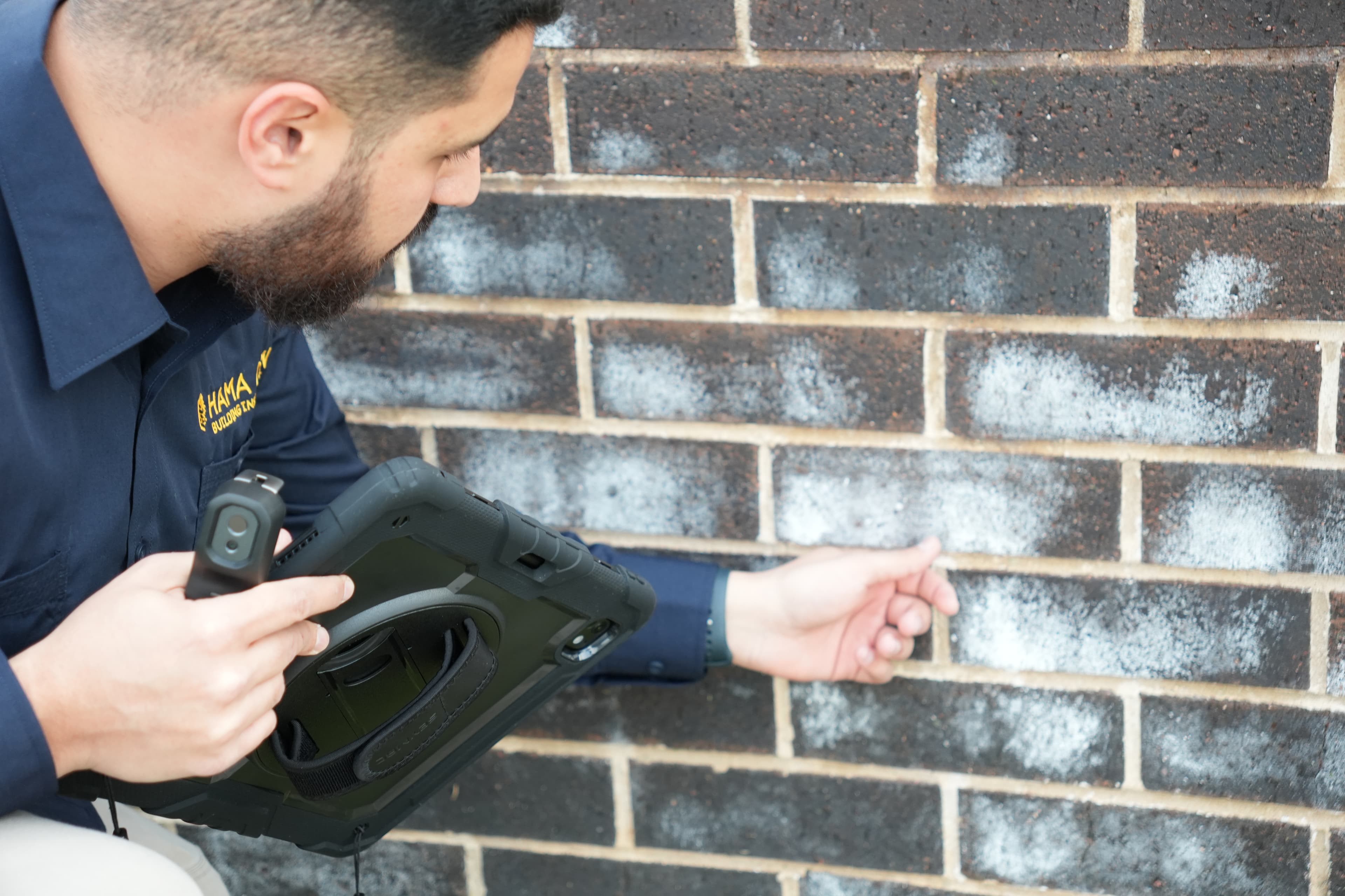 Hama Con inspector examining a brick wall for moisture and defects